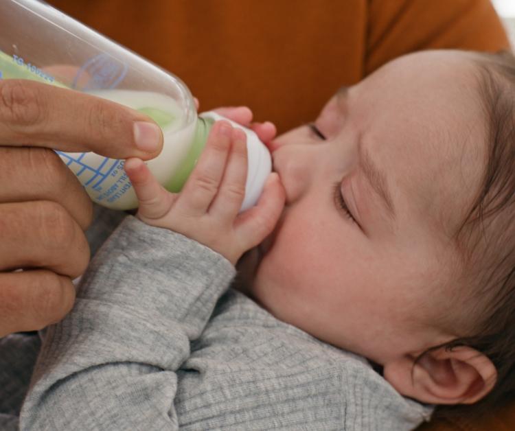Madre cargando a su hijo mientras toma del biberón