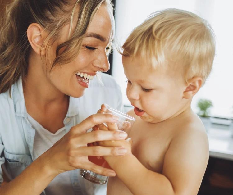 Mom helping her baby take a drink of juice