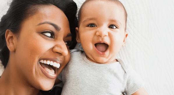 Madre y bebé acostados, ambos sonriendo
