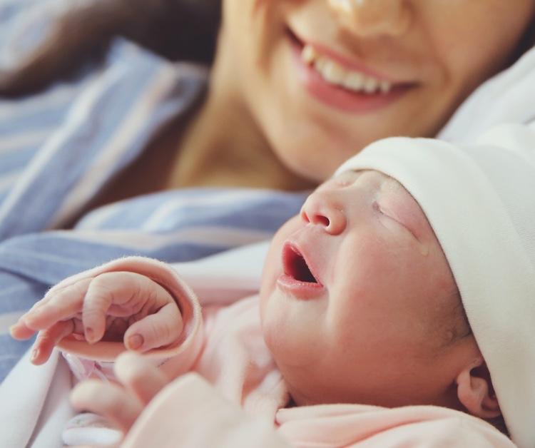 Bebé recién nacido sostenido por una mamá sonriente