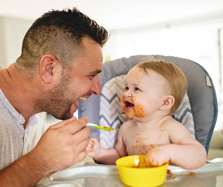 Papá alimenta felizmente a su pequeño