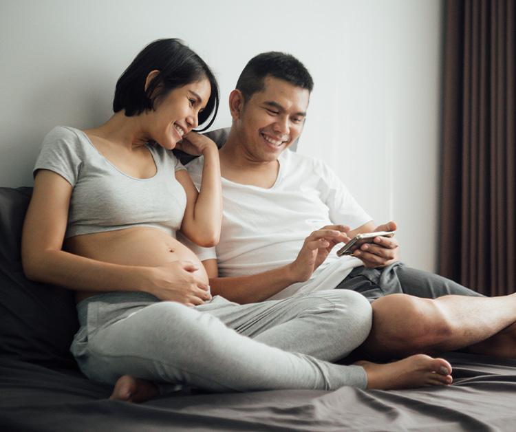 Expecting couple sitting and looking at phone