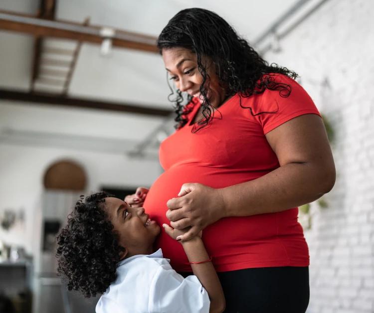Madre embarazada sonriendo con su niño pequeño