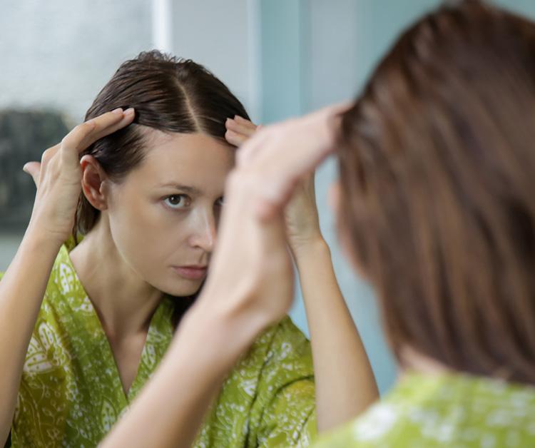 Woman examining her hair in the mirror