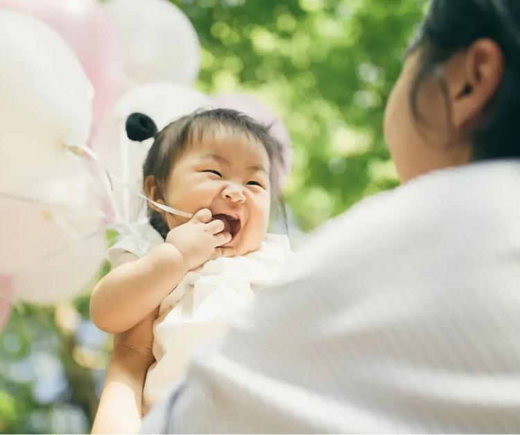 Mom holding baby with balloons