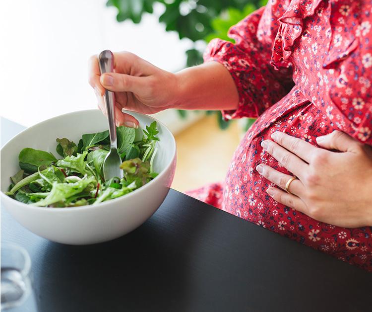 Mujer embarazada comiendo ensalada