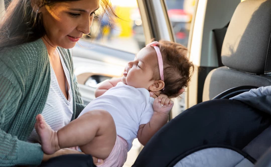 Madre colocando al bebé en la silla para el coche