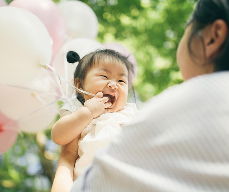 Niño feliz sosteniendo globos con su mamá
