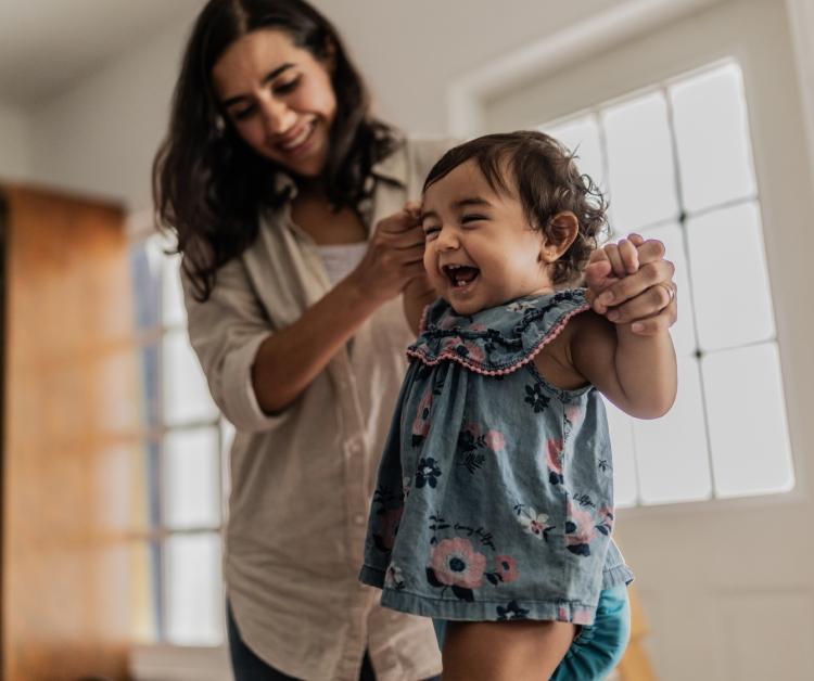 mom holding baby's hands while she walks