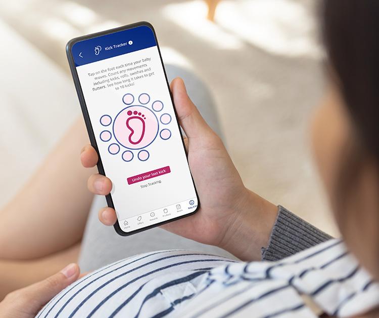 Pregnant mom holding phone with app displayed on screen