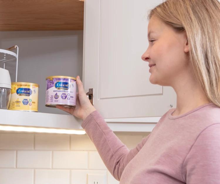 Mom taking a can of Enfamil out of cabinet