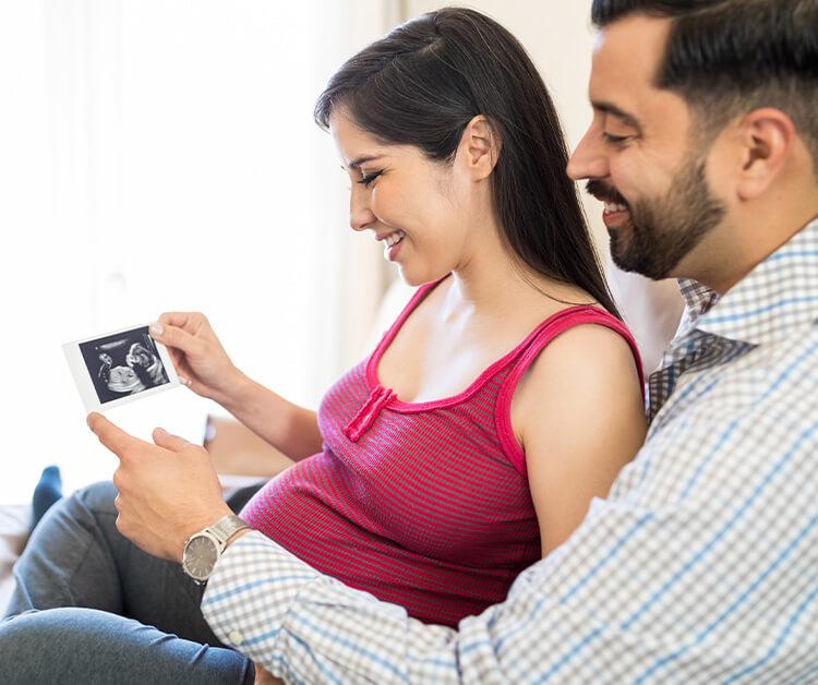 Pareja sonriente mirando una foto de ultrasonido