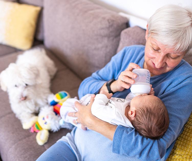 Grandma bottle-feeding baby on the couch