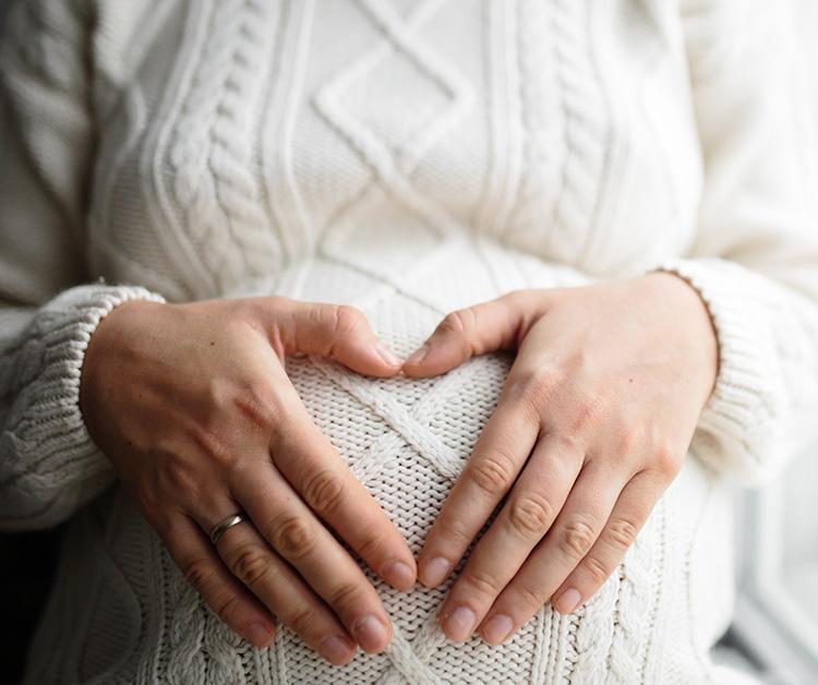 Pregnant woman making a heart with her hands on her baby bump