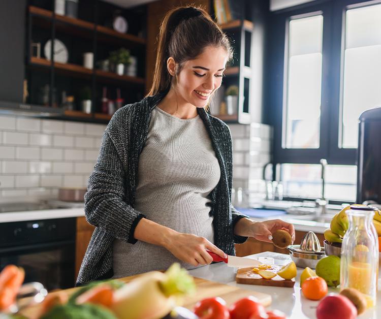 Pregnant woman preparing a meal of fruits