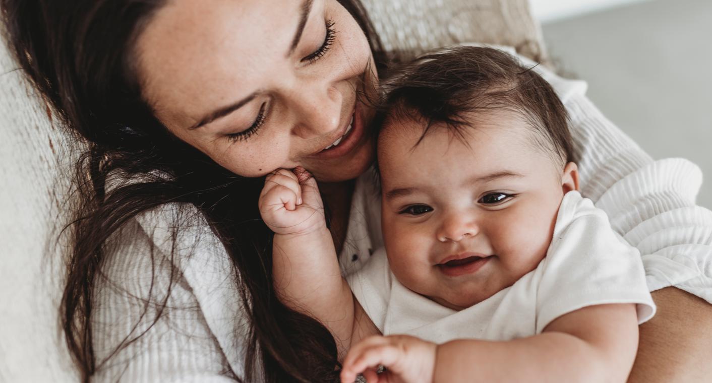 Mamá y su bebé ríen con un envase de Enfamil AR #1 Marca de Confianza por Pediatras*