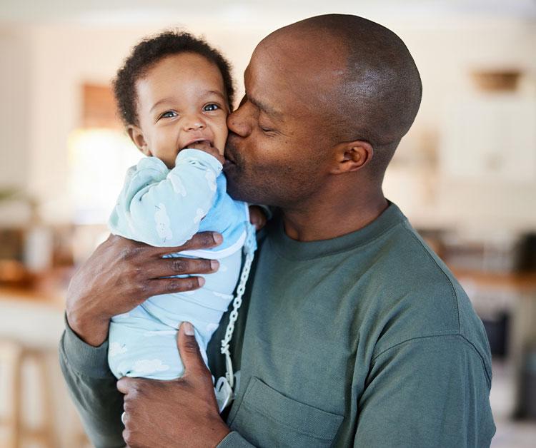 Dad holding baby and kissing him on the cheek