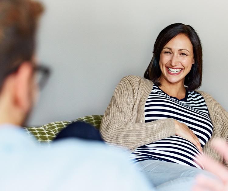 Smiling pregnant woman sitting and talking with someone
