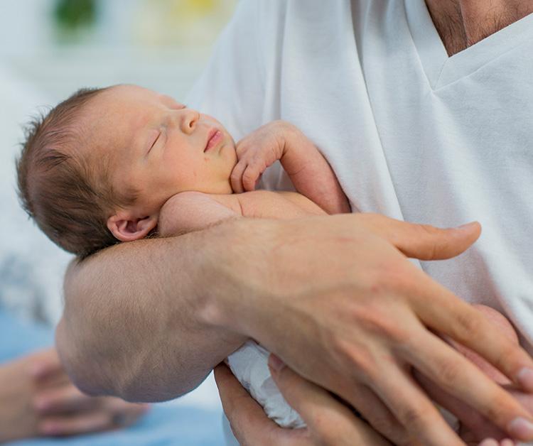 Dad holding premature baby at the hospital