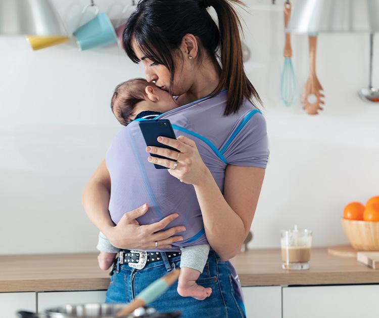 Mom kissing the head of a baby in her wrap carrier