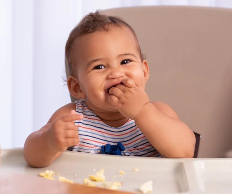 Baby eating eggs in a high chair