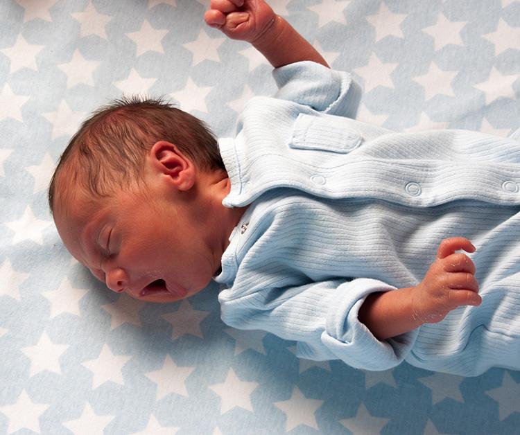 Premature baby on blanket yawning