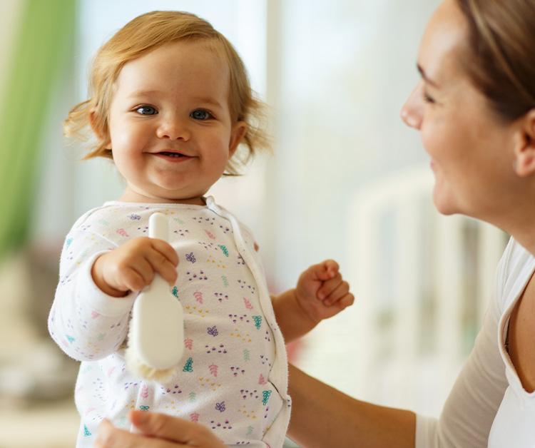 Bebé sonriente sostenido por mamá