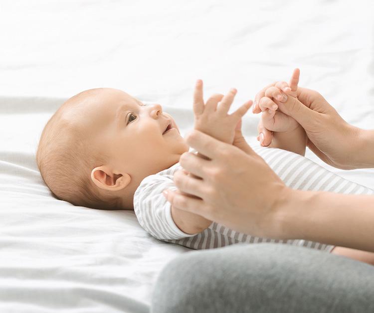 Baby laying on their back as mom holds their hands