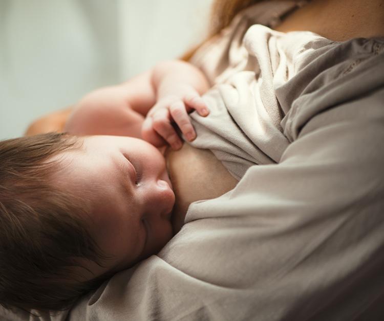 Mom sitting on the couch breastfeeding baby