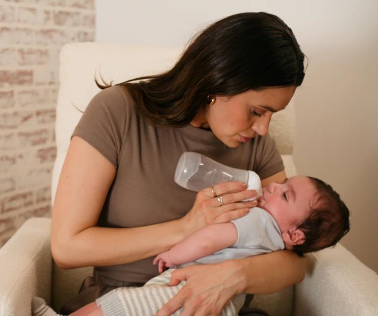 Mamá mece al bebé y le da el biberón.