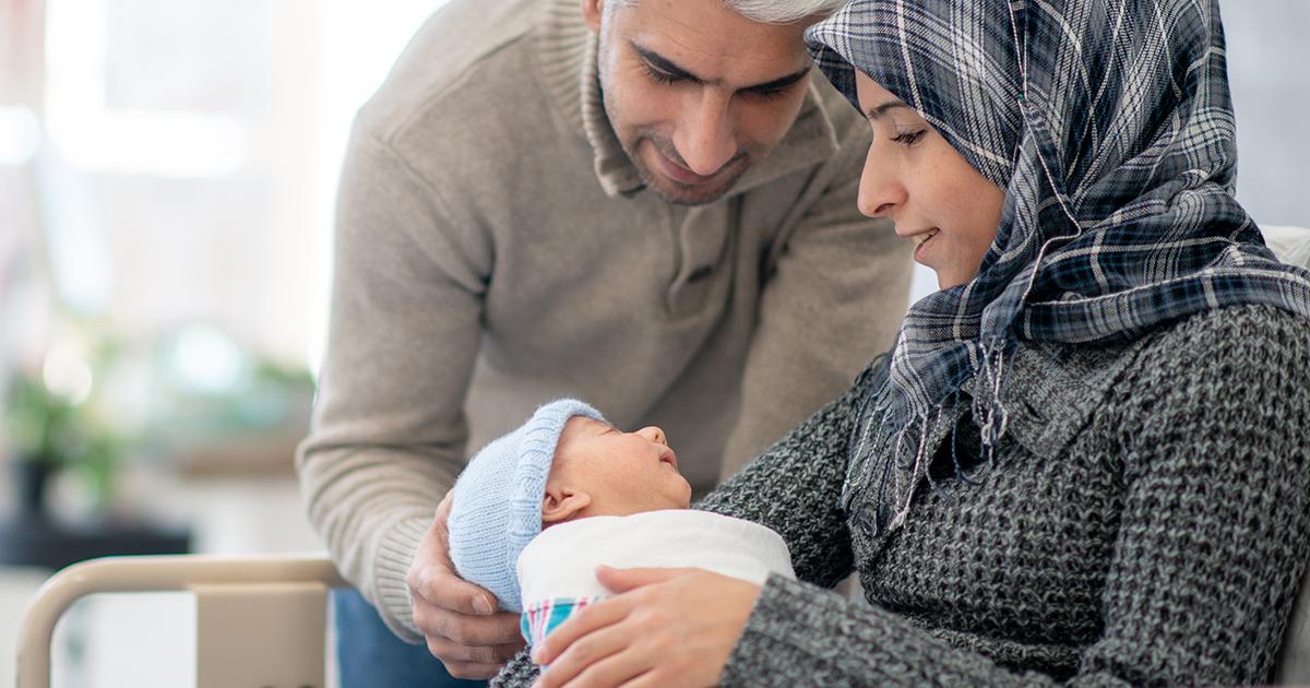 Padre y madre mirando con adoración a su bebé recién nacido.